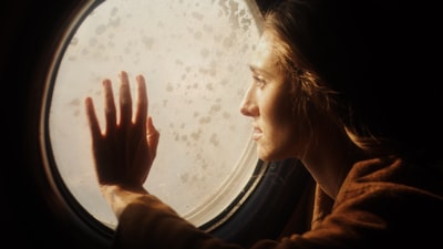 The woman is wearing a brown shirt with a round mirror
